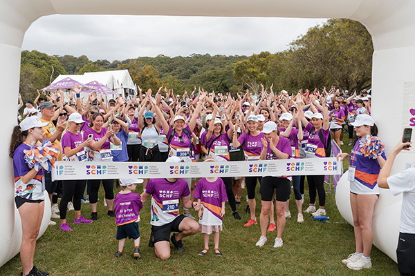 Hundreds of Walk for Kids with Cancer participants celebrating as a patient family cuts the ribbon at the event