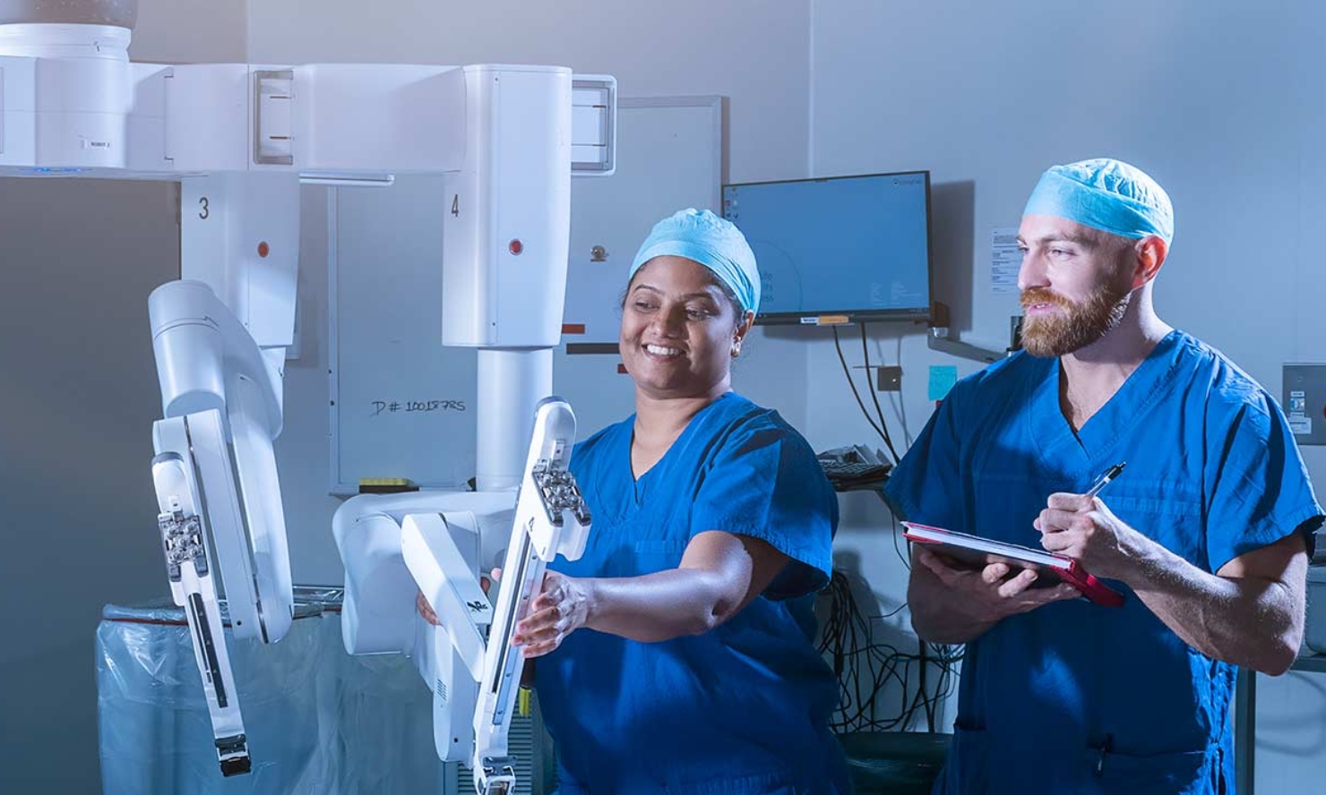 Two surgical team members are working with a da Vinci Robotic system Two surgical team members are working with a da Vinci Robotic system