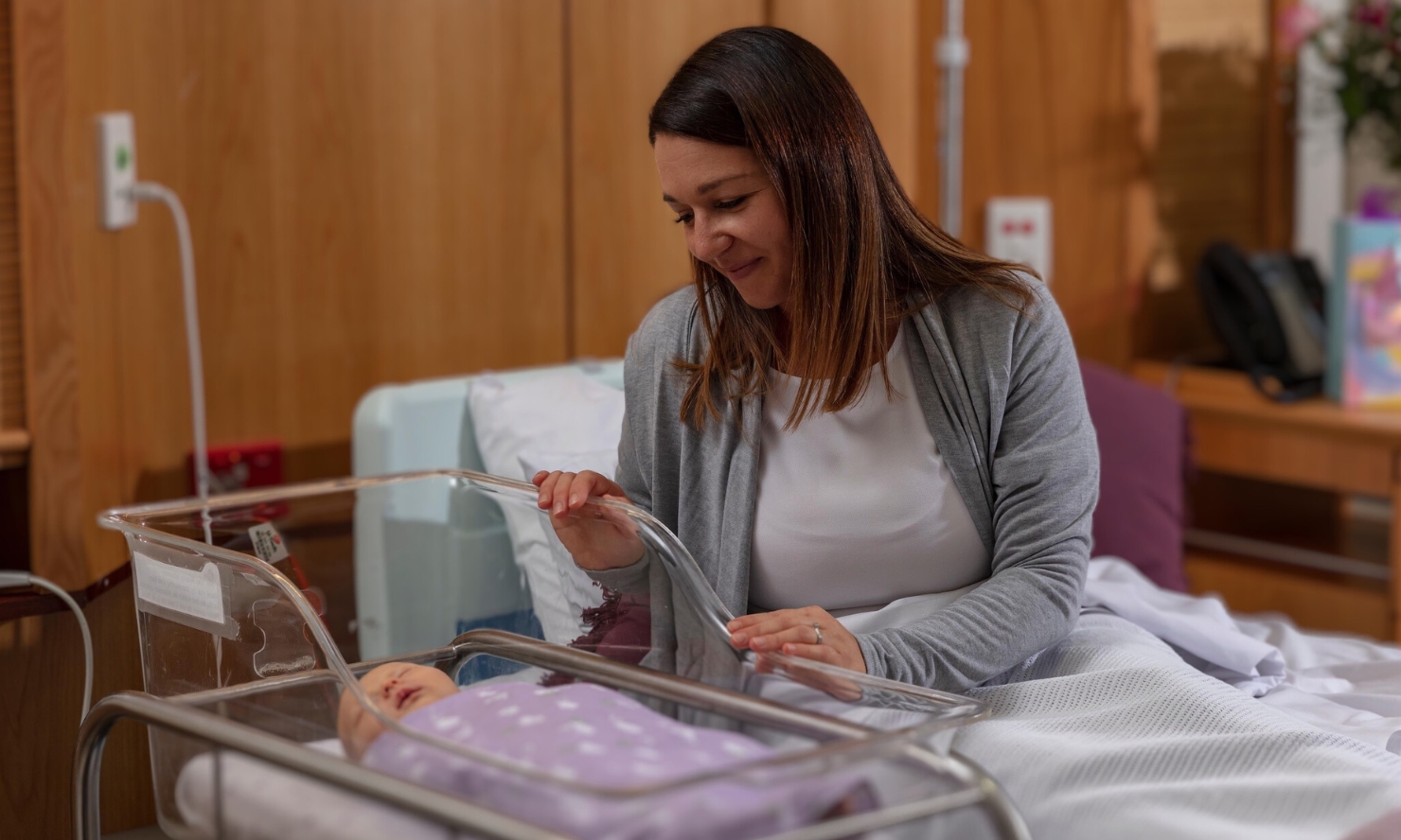 A mother is looking lovingly over her new born baby in a hospital room A mother is looking lovingly over her new born baby in a hospital room