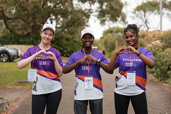 Three Walk for Kids with Cancer volunteers making heart gestures with their hands