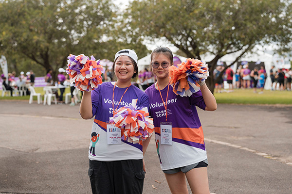 Two volunteers holding colourful pompoms