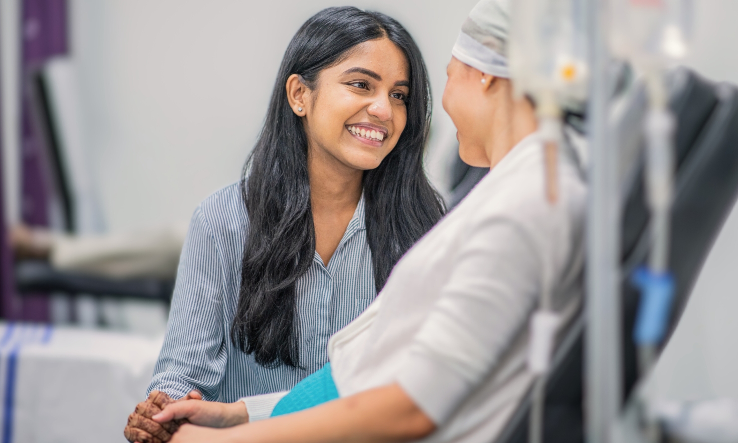 A photo of a woman living with cancer and a healthcare team member caring for them with a warm smile A photo of a woman living with cancer and a healthcare team member caring for them with a warm smile