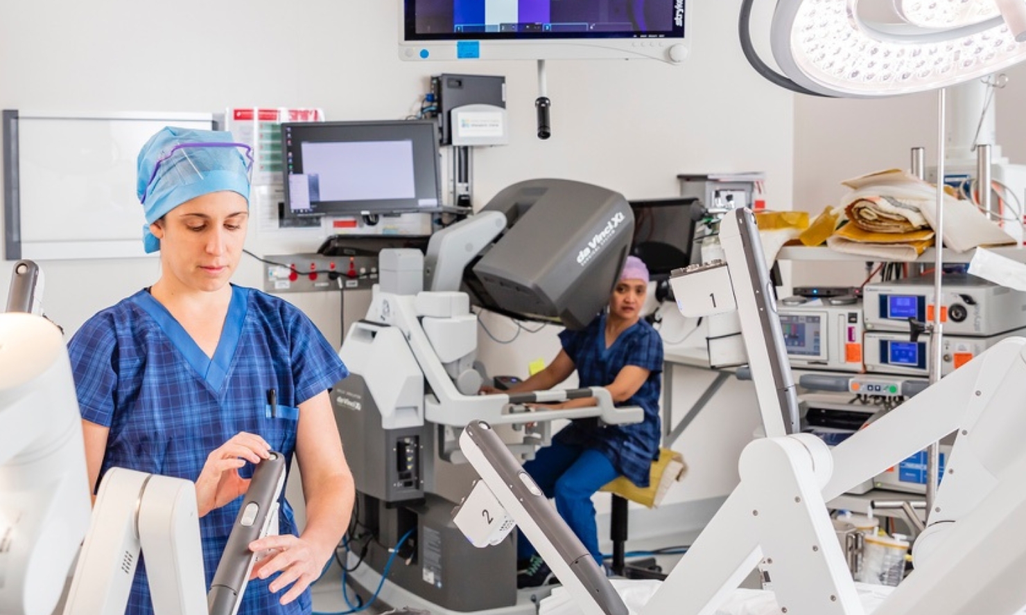 A photo of two healthcare professionals working with da Vinci robot in an operating theatre A photo of two healthcare professionals working with da Vinci robot in an operating theatre