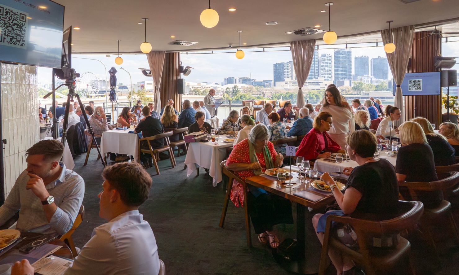 A photo taken of at the Gambaros Luncheon this year. There are lots of people enjoying meals while listening to the events speakers.