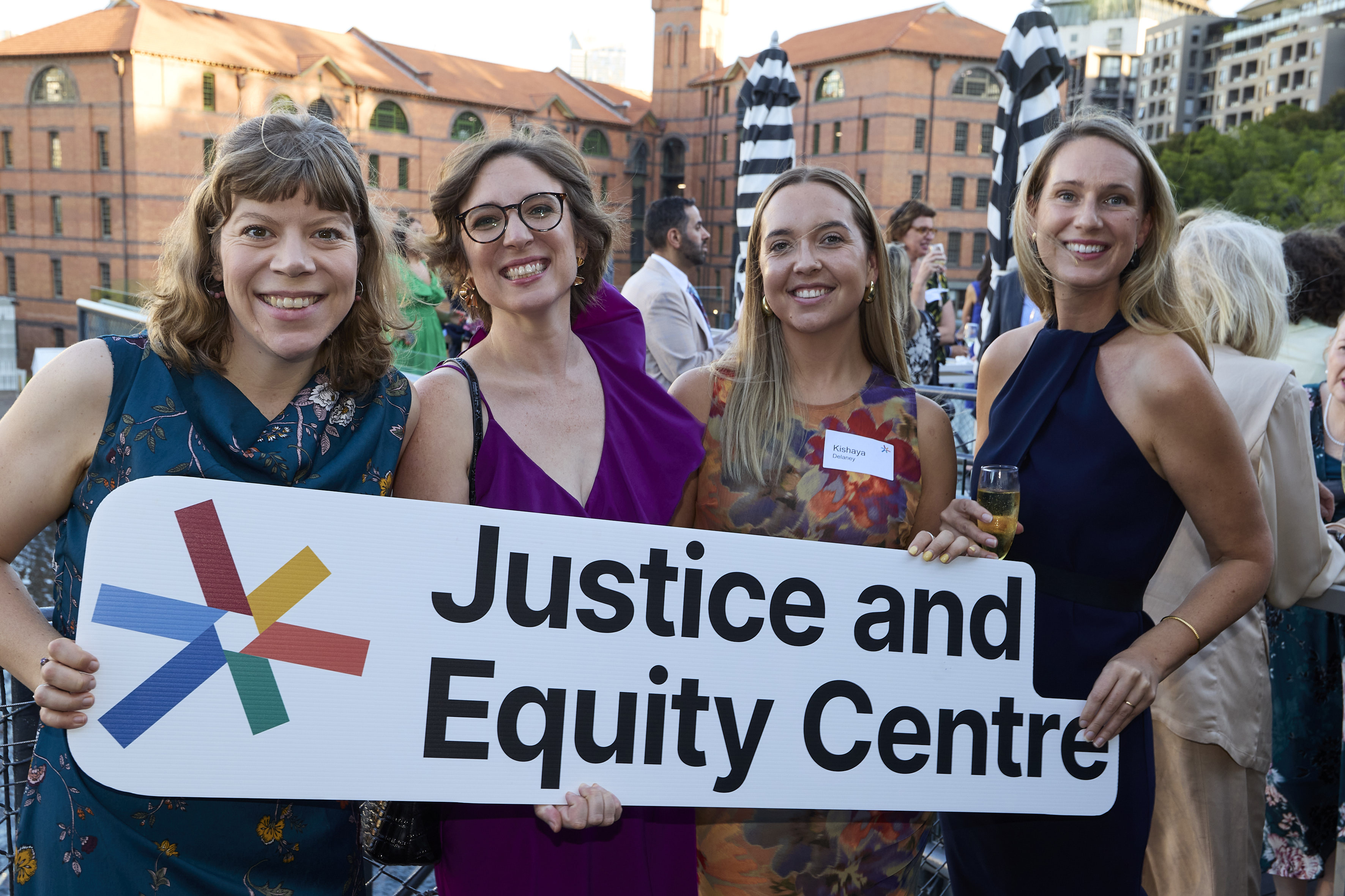 Smiling supporters holding a Justice and Equity Centre sign